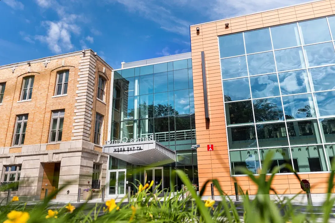 Barnes Center main entrance, with blue sky and trees reflected in the glass around the door.